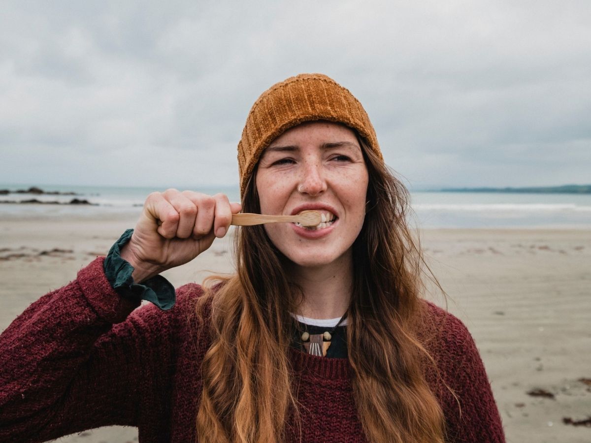 frau putzt zähne mit zero waste bambuszahnbürste