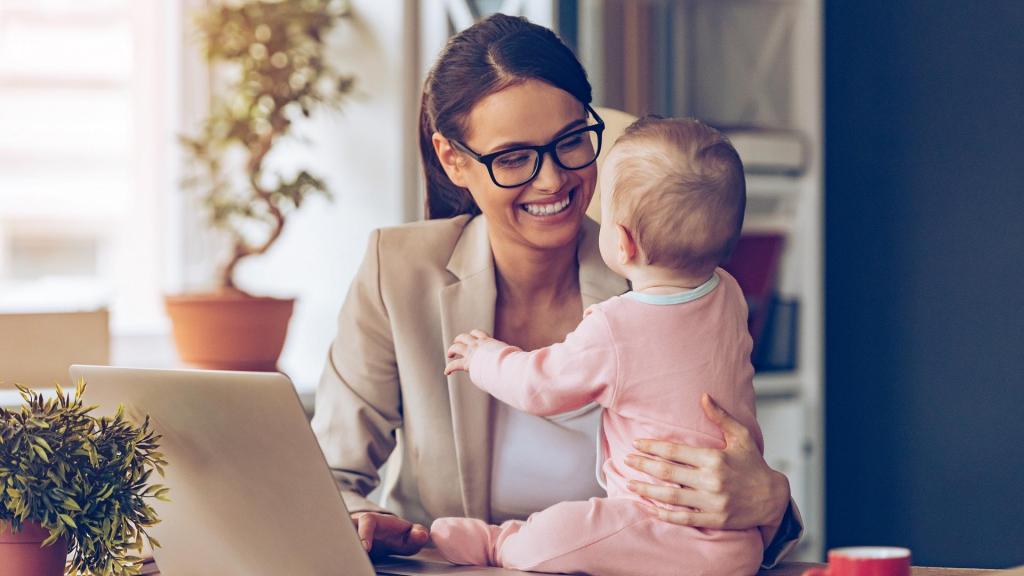 Frau sitzt vor einem Laptop mit Baby daneben