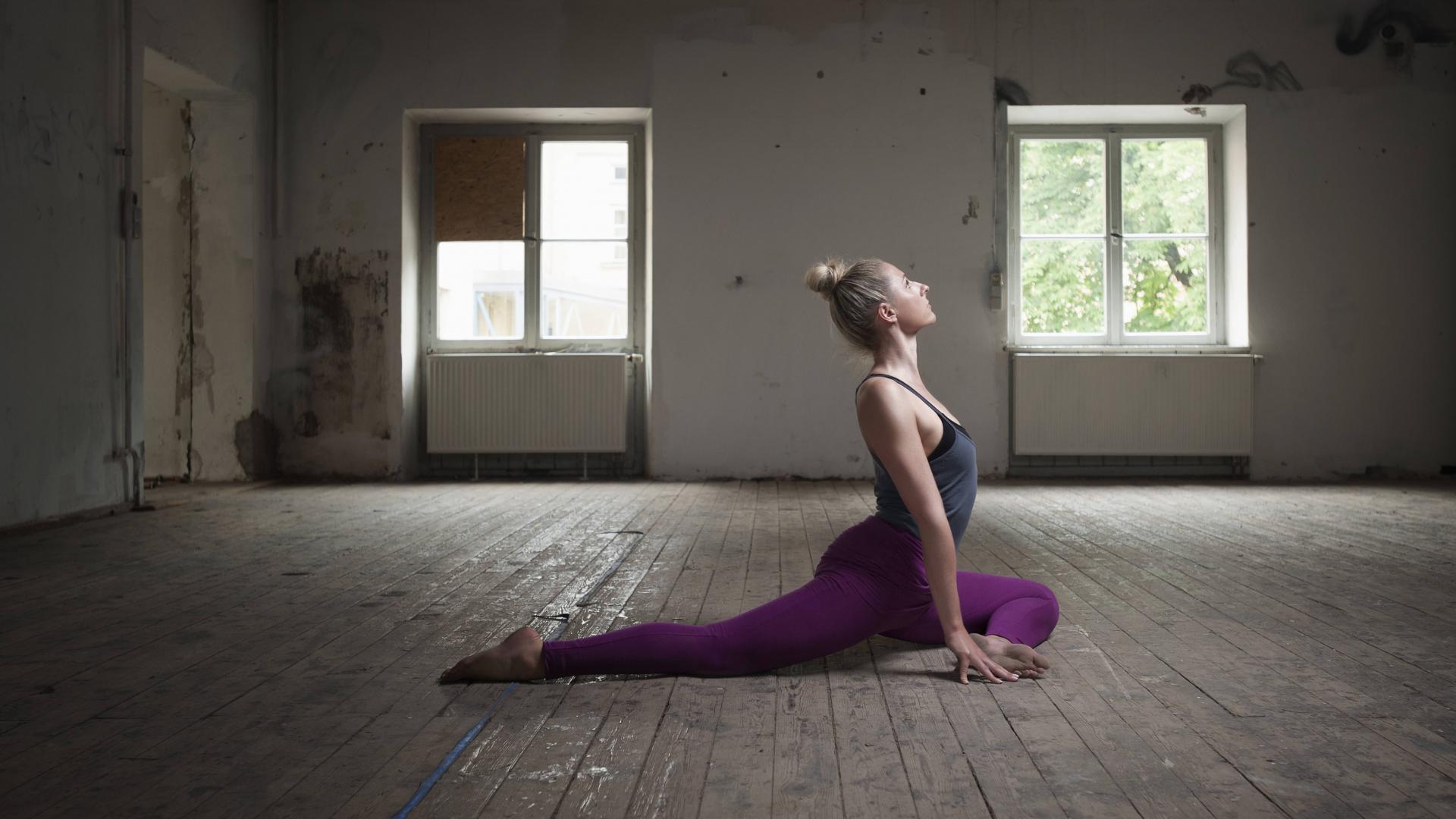 Frau in Yoga-Taubenstellung in einer alten verlassenen Wohnung