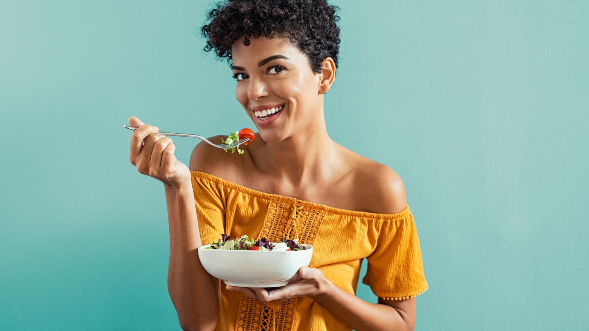 strahlende Frau isst Salat