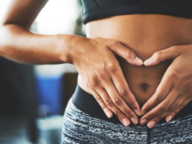 sportliche Frau hält sich die Hände vor den Bauch