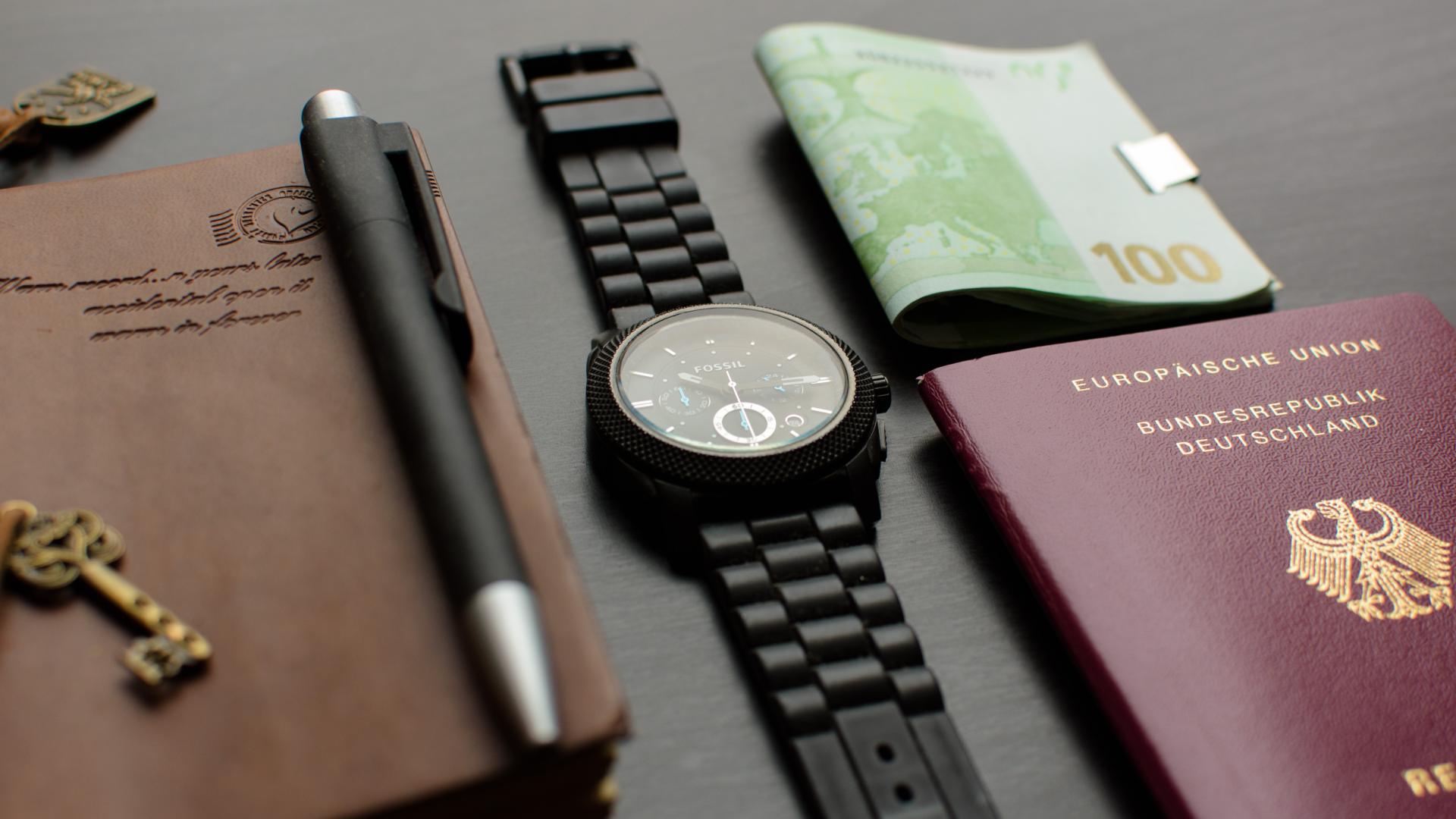 Reisepass, Uhr, Geld und Tagebuch auf einem Tisch