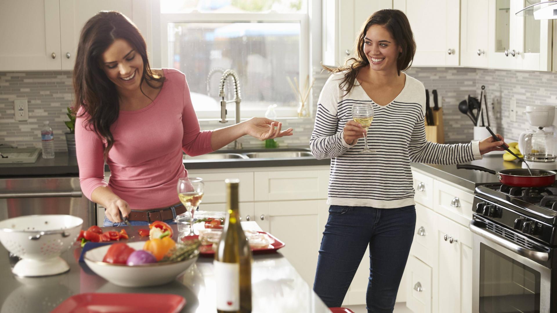 Frauen kochen zusammen und trinken Wein