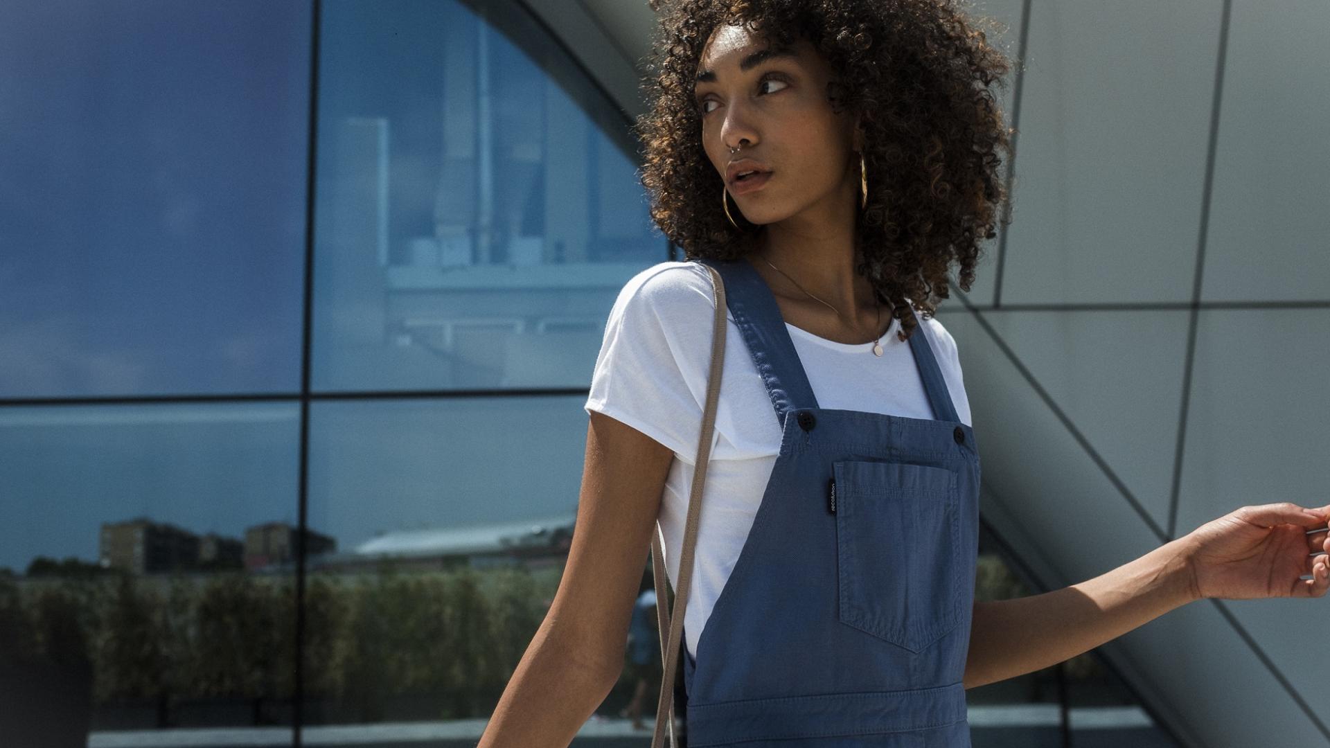 junge Frau mit Afro-Locken und modischer Kleidung vor einem Gebäude