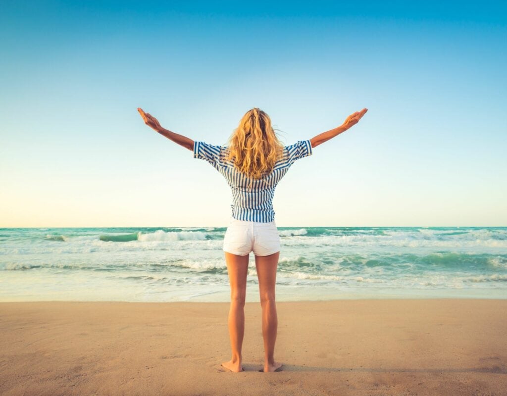 Frau am Strand mit den Armen in der Luft