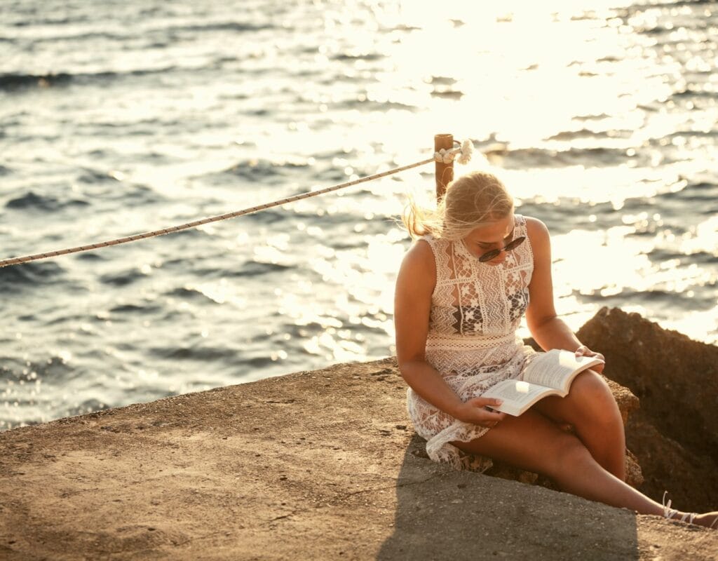 Frau liest am Meer ein Buch