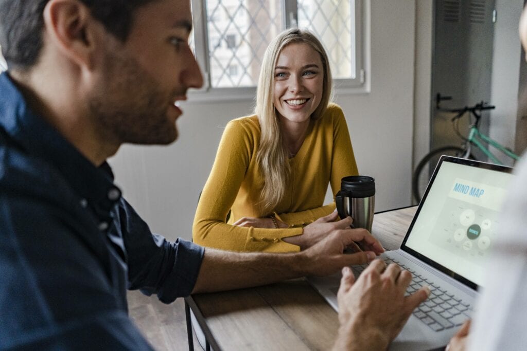 frau sitzt mit mann am tisch mit laptop