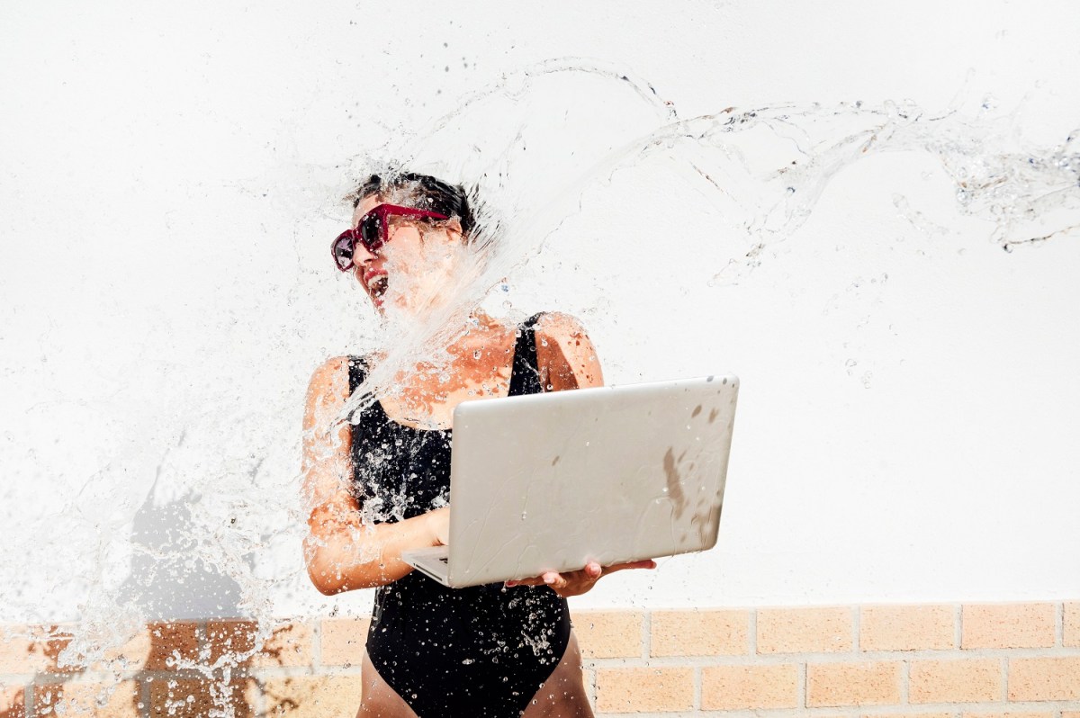 Frau mit Laptop in der Hand wird nass gespritzt