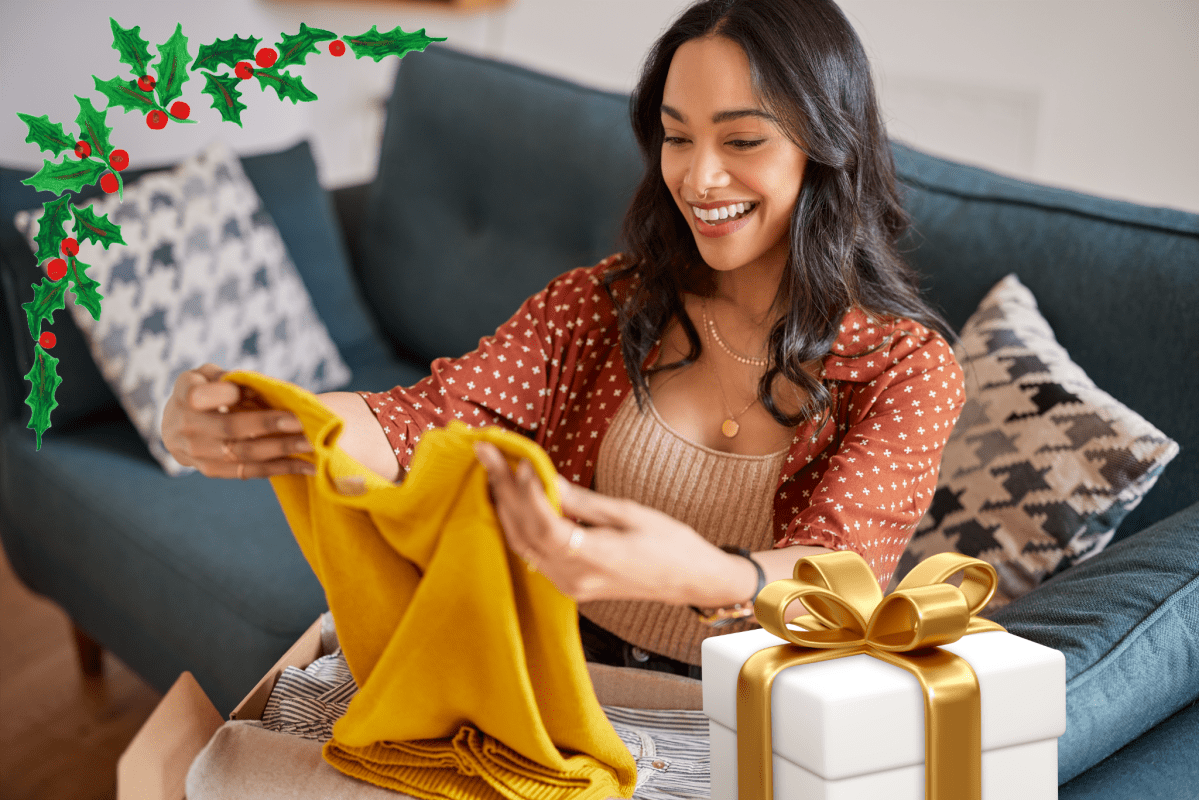 Eine Frau packt ein gelbes Kleidungsstück aus einem Paket aus. Daneben steht ein Geschenk.