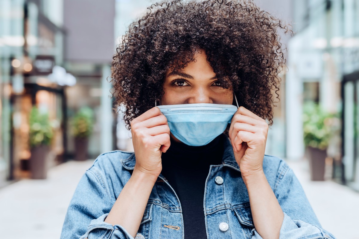 frau afro haare maske jeansjacke lächeln