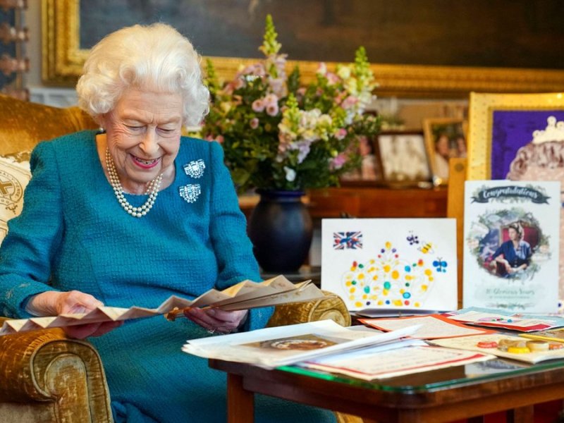 Queen Elizabeth II. amüsiert sich über alte Glückwunschkarten.. © imago images/i Images