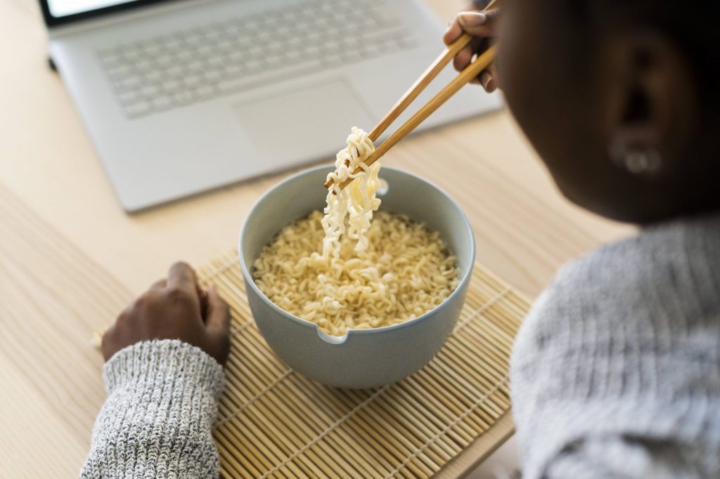 frau mittag essen nudeln laptop