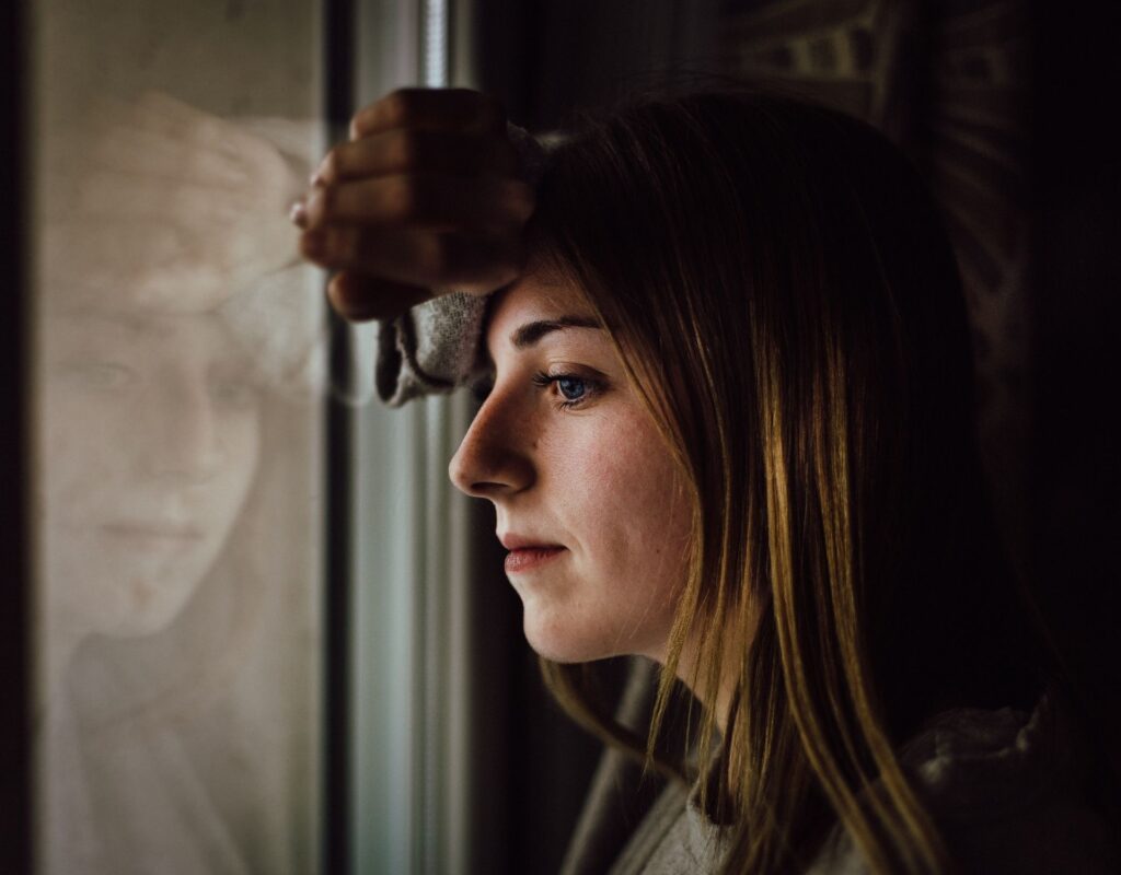 Frau steht am Fenster