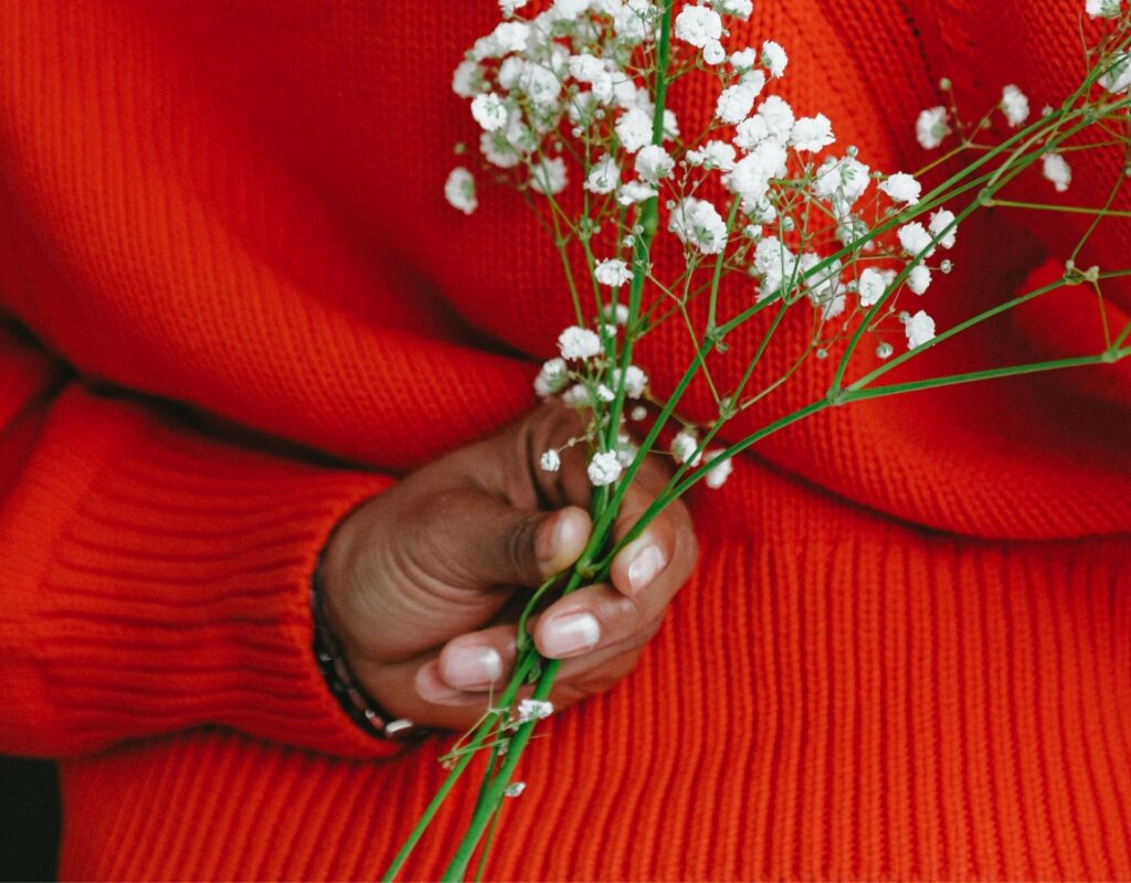 Frau mit rotem Pulli hält Blumen