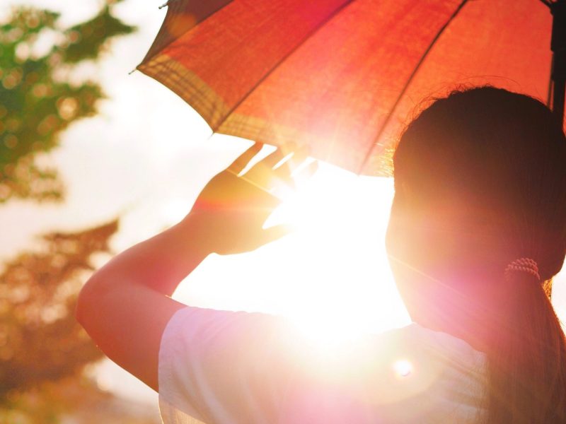 Frau schützt sich mit Schirm vor der Sonne