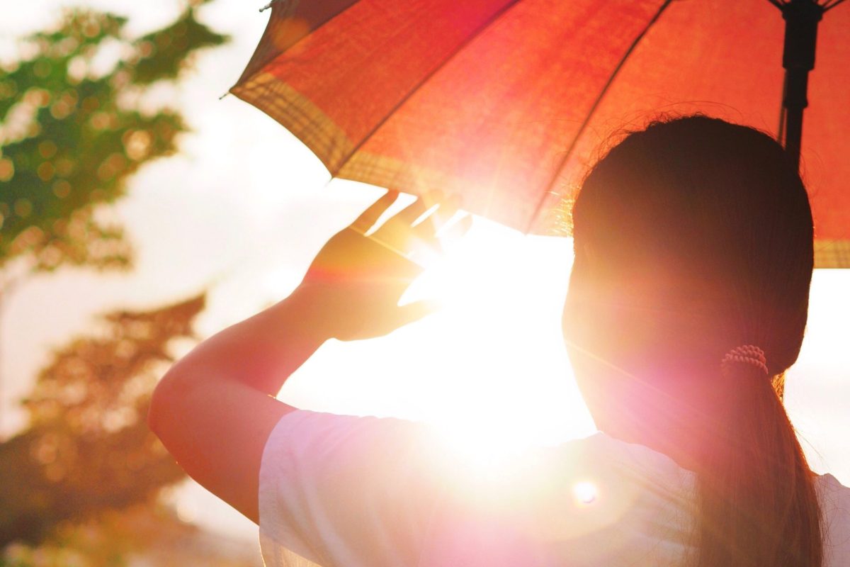 Frau schützt sich mit Schirm vor der Sonne