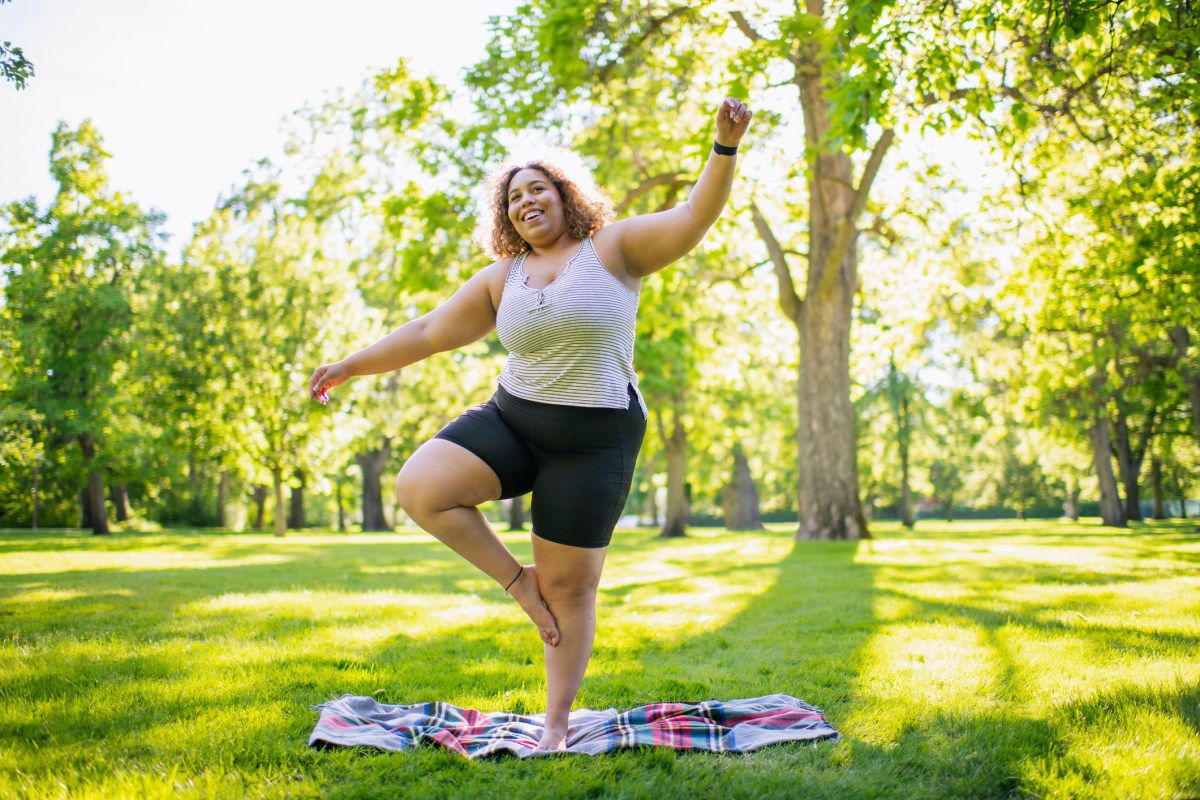 Frau im Park steht auf einem Bein