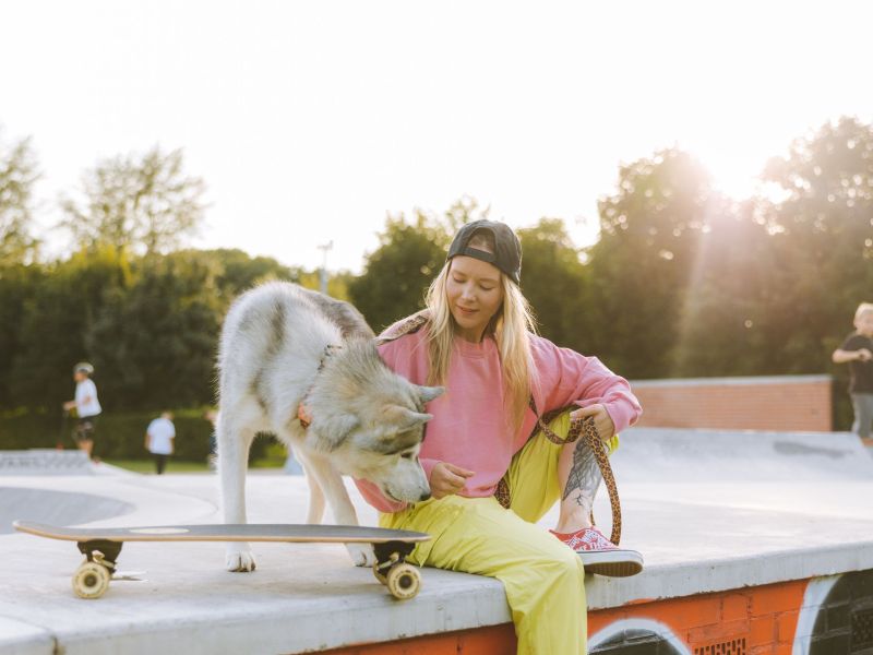 Frau mit Husky auf Skateboard