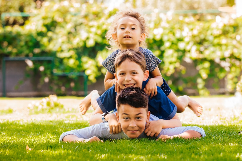 Sandwichkinder liegen auf dem Rasen übereinander