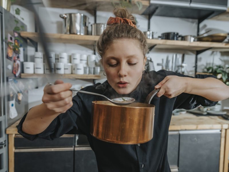 Frau probiert Suppe aus Topf