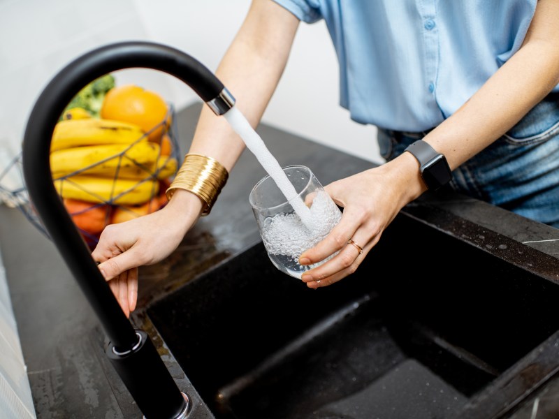 Frau trinkt aus Wasserhahn