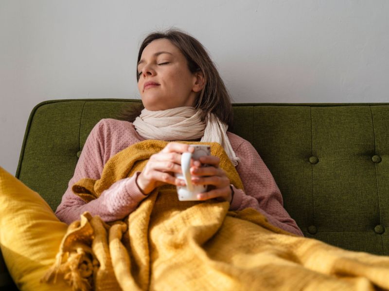 Frau krank auf dem Sofa mit Tee