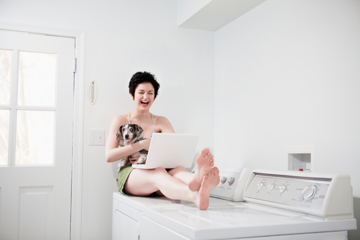 Frau sitzt auf einer Waschmaschine