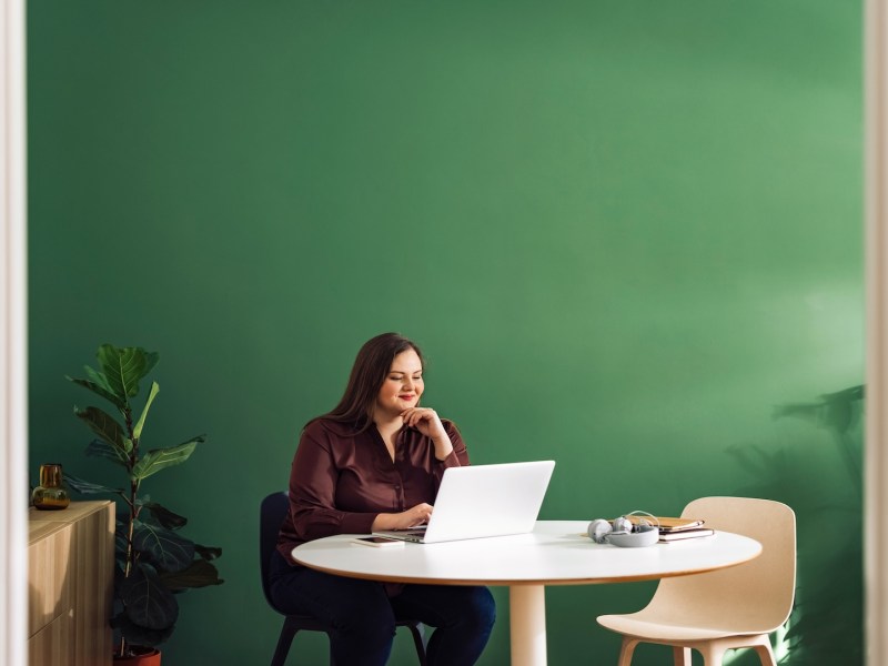 Frau sitzt am Schreibtisch und tippt auf der Tastatur eines Laptops.