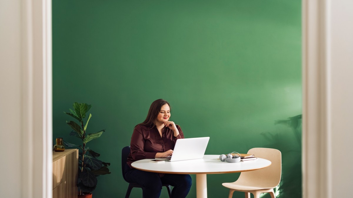 Frau sitzt am Schreibtisch und tippt auf der Tastatur eines Laptops.