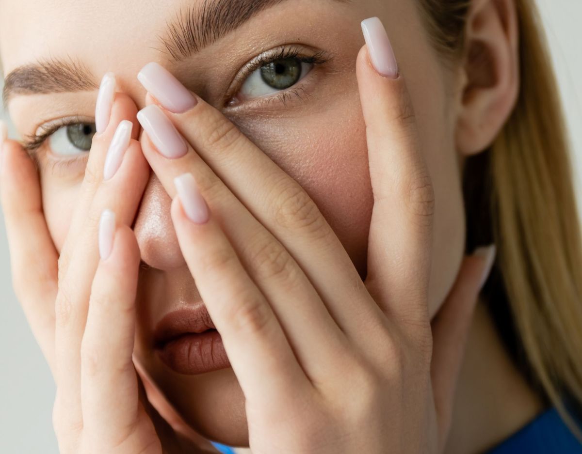 Frau mit Fingern über dem Gesicht: Persönlichkeitstest kleiner Finger