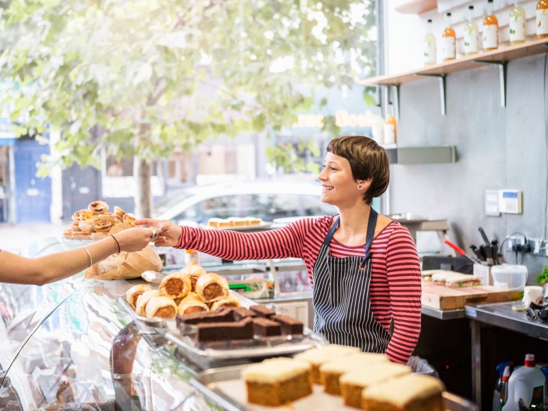 Frau verkauft in einer Bäckerei Brötchen