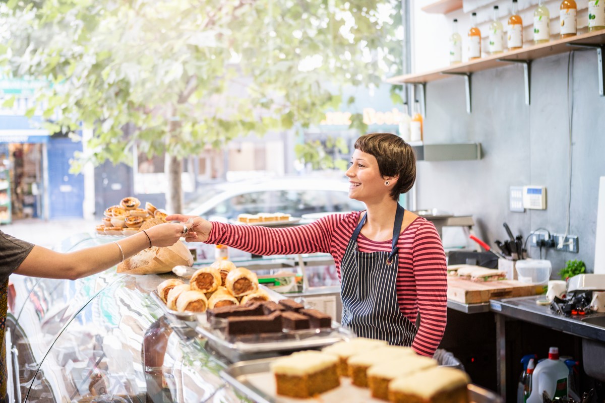 Frau verkauft in einer Bäckerei Brötchen