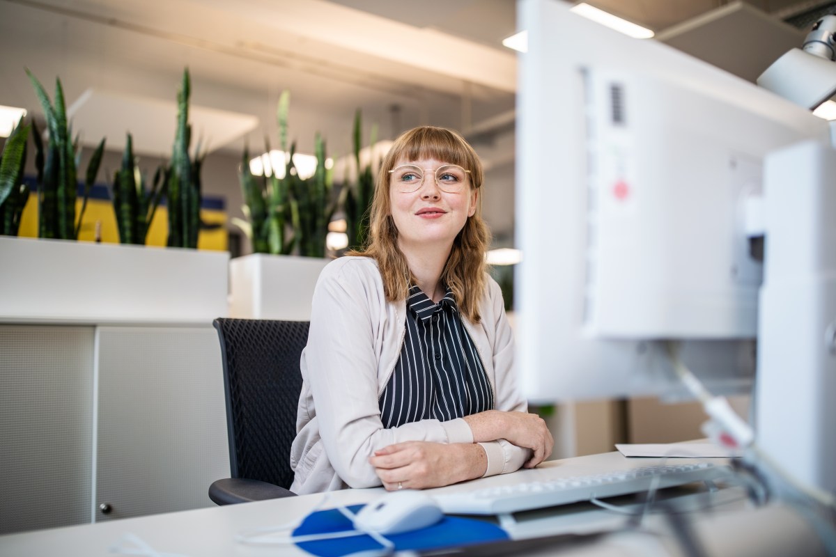 Frau sitzt im Büro an ihrem Arbeitsplatz