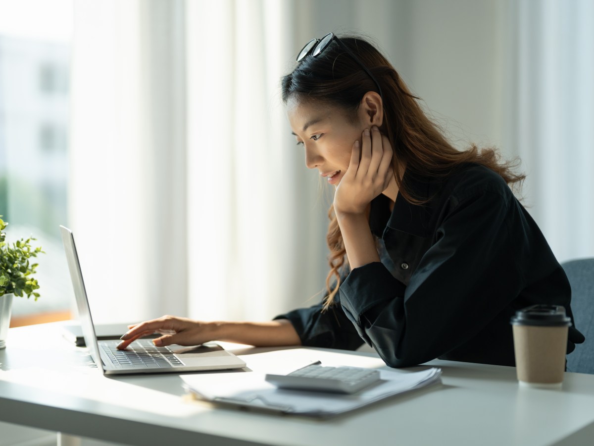 Frau sitzt am Laptop und rechnet etwas durch