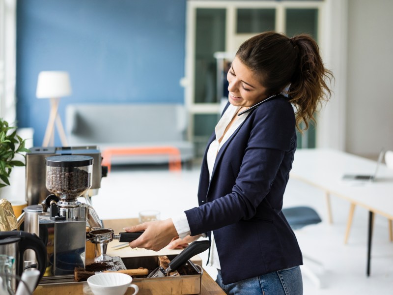 Frau macht sich im Büro einen Kaffee.