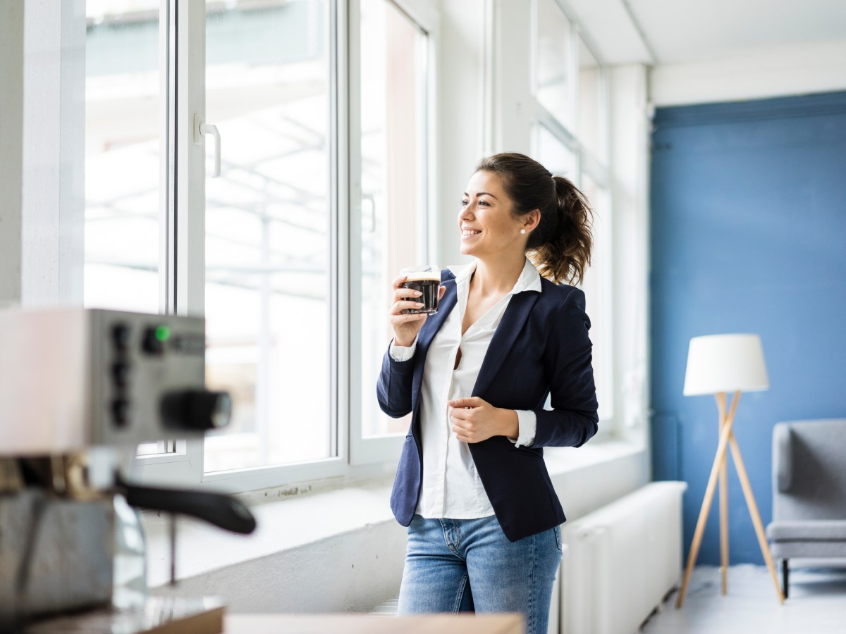 Frau trinkt im BÃ¼ro eine Tasse Kaffee.