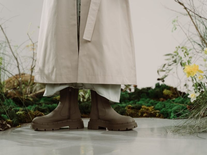 Frau steht mit Gummistiefeln zwischen Rasenflecken