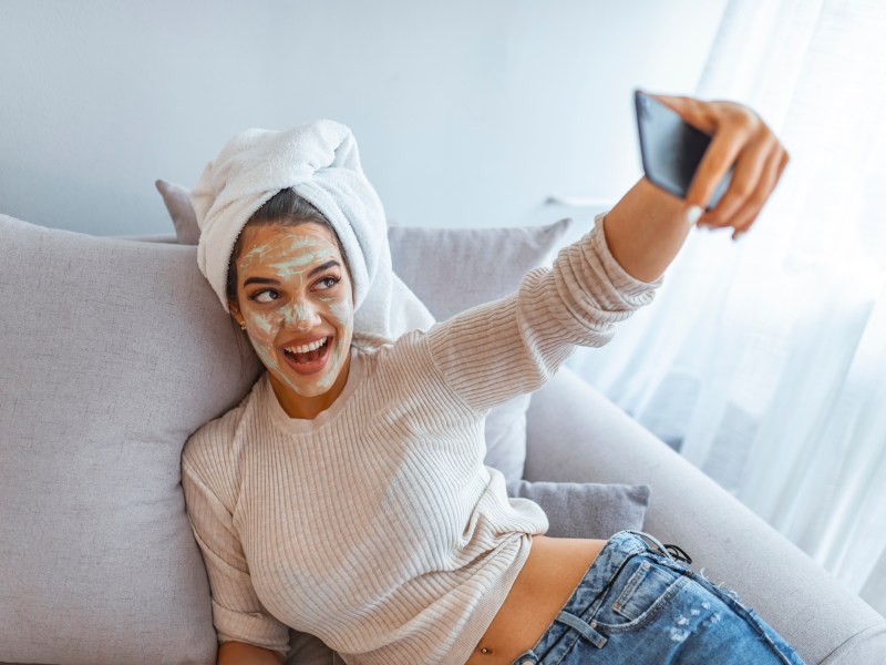 Frau mit grüner Tee Maske macht Selfie