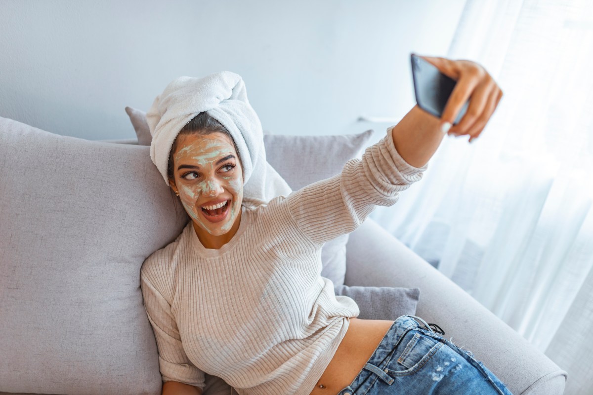 Frau mit grüner Tee Maske macht Selfie