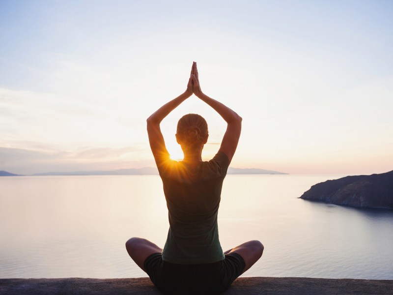 Frau macht Yoga im Sonnenuntergang.