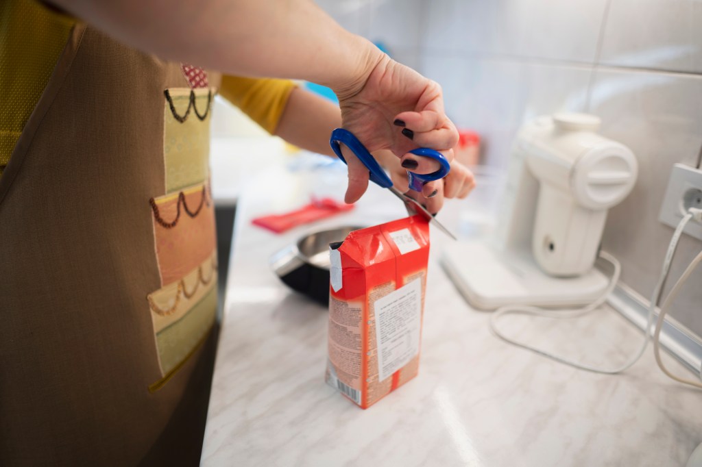 Frau schneidet Tetrapak auf