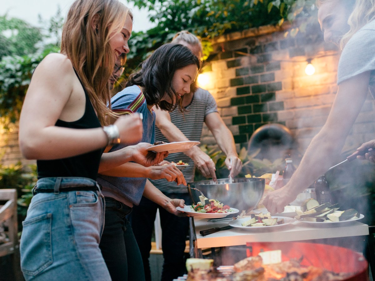 Eine Gruppe junger Leute grillt gemeinsam.