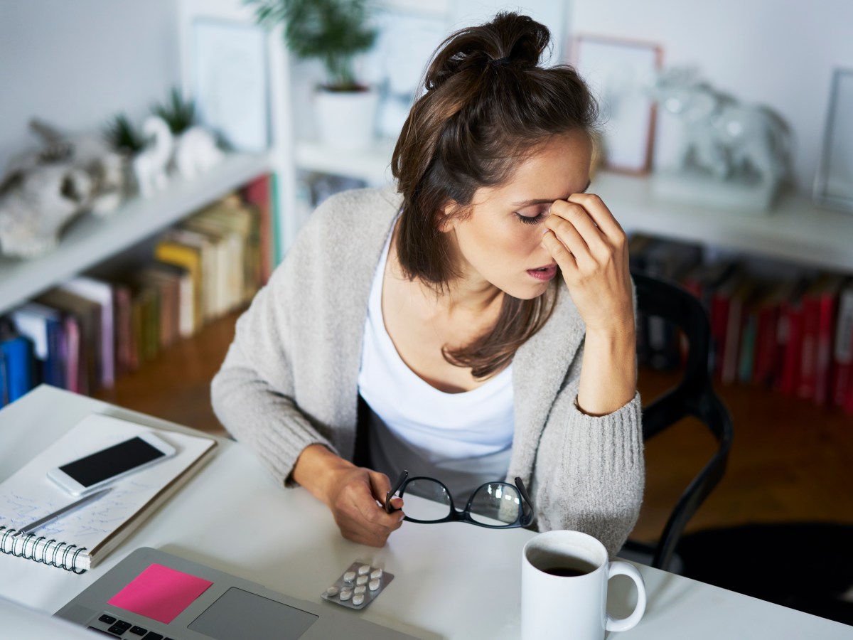 Junge Frau sitzt sehr erschÃ¶pft am Arbeitsplatz