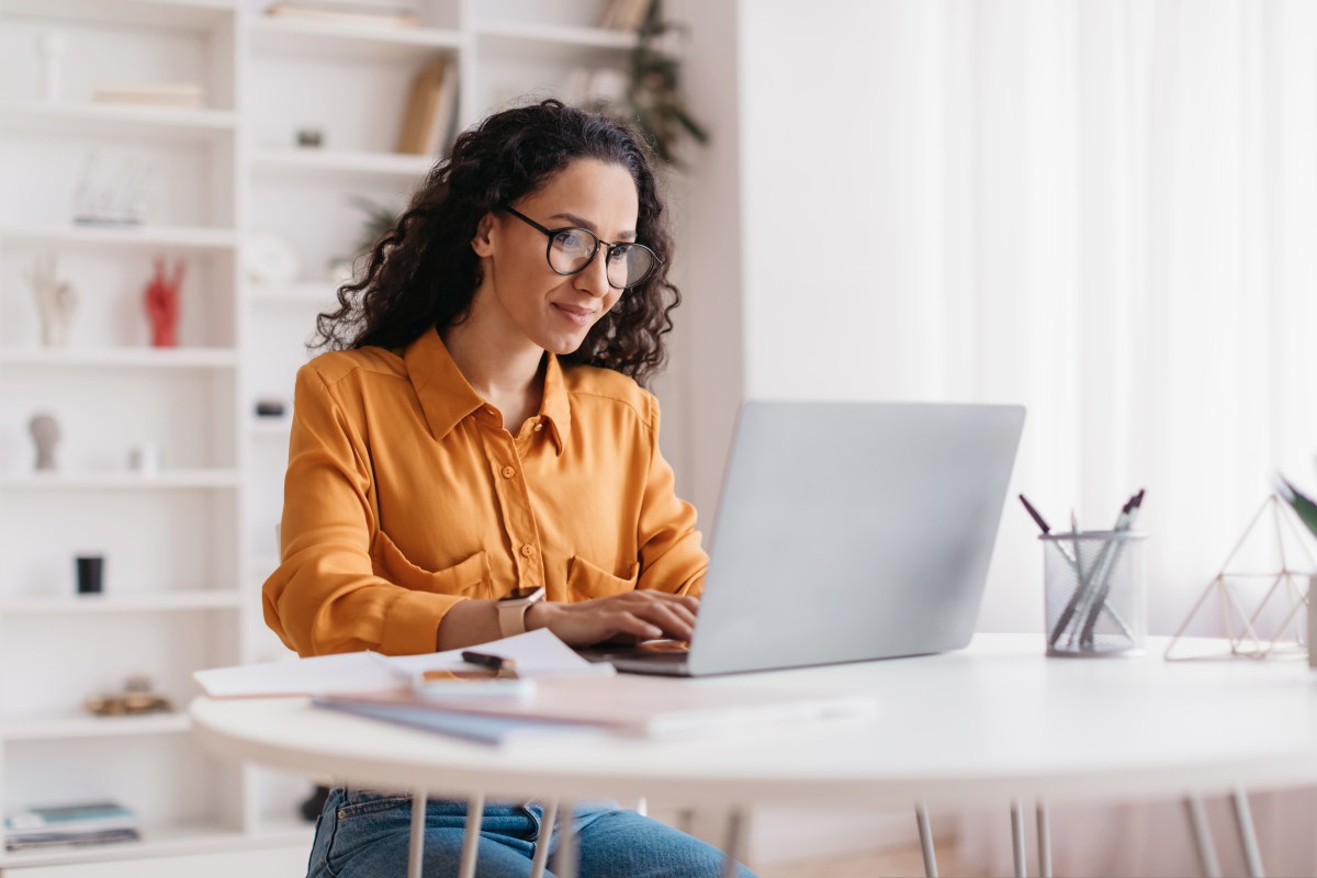 Frau mit Brille sitzt am Laptop.