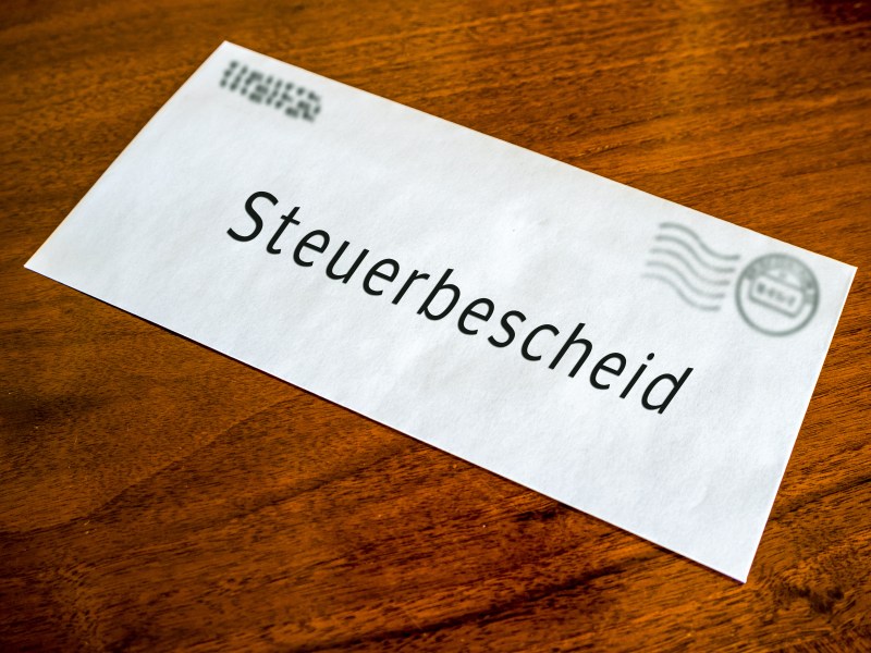 Ein Brief mit der Aufschrift "Steuerbescheid" liegt auf dem Tisch.