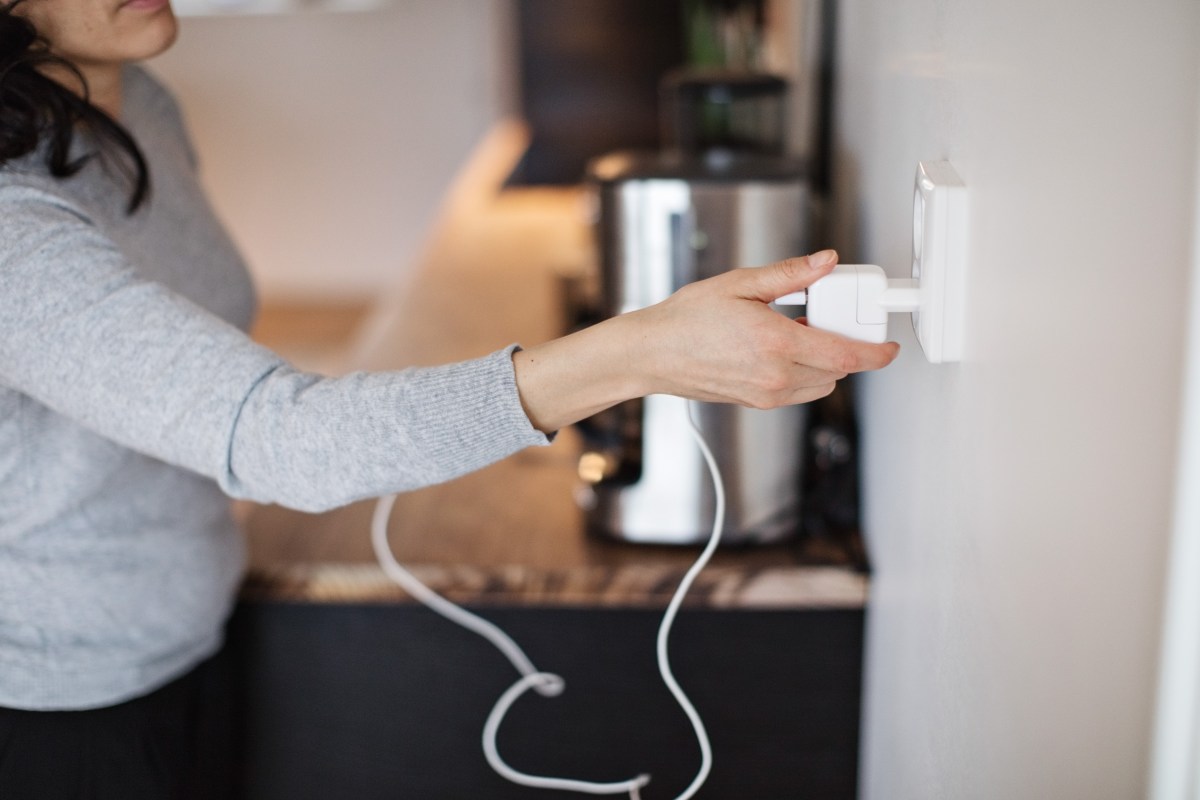 Eine Frau steckt einen Stecker aus der Steckdose.