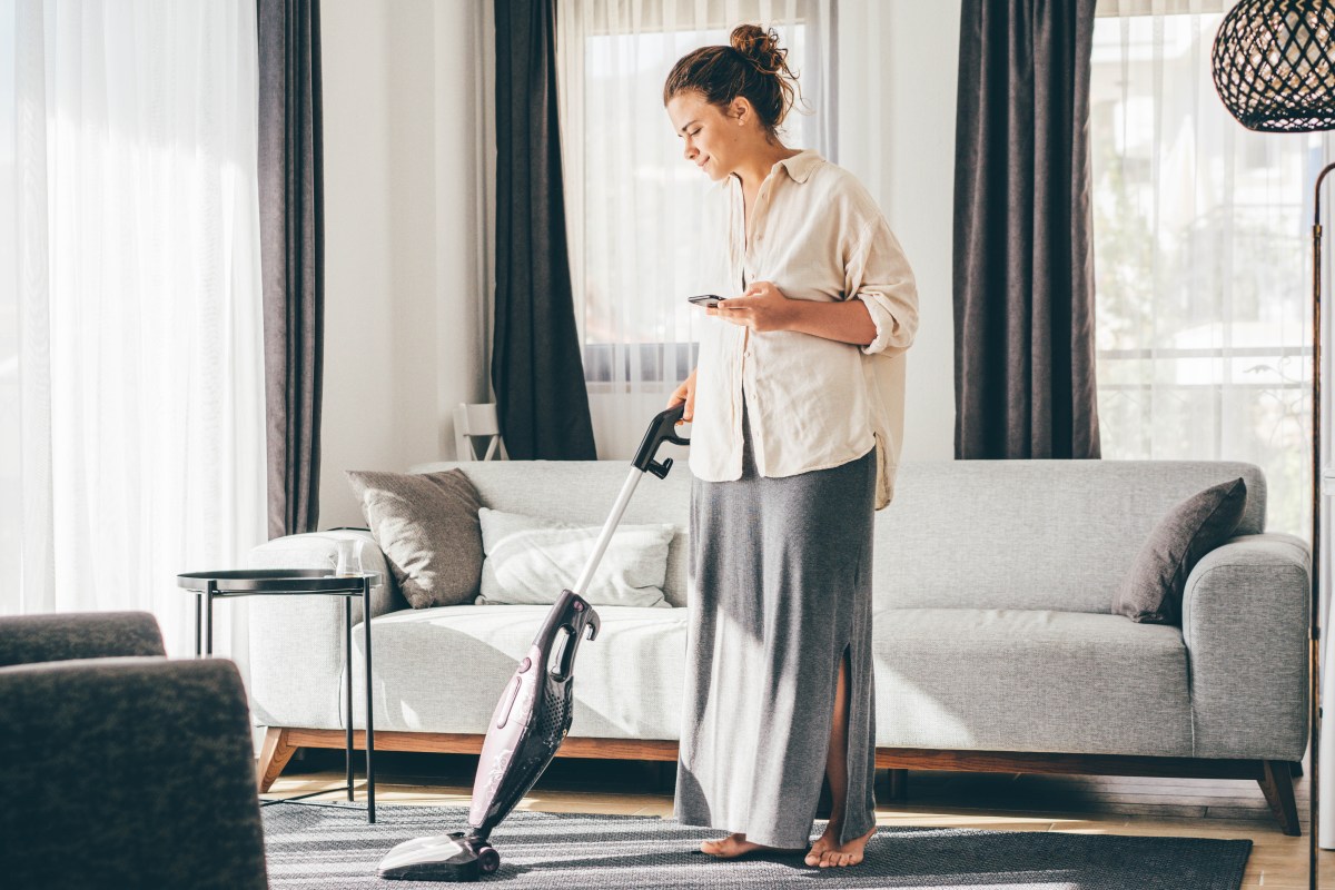 Eine Frau saugt das Wohnzimmer.