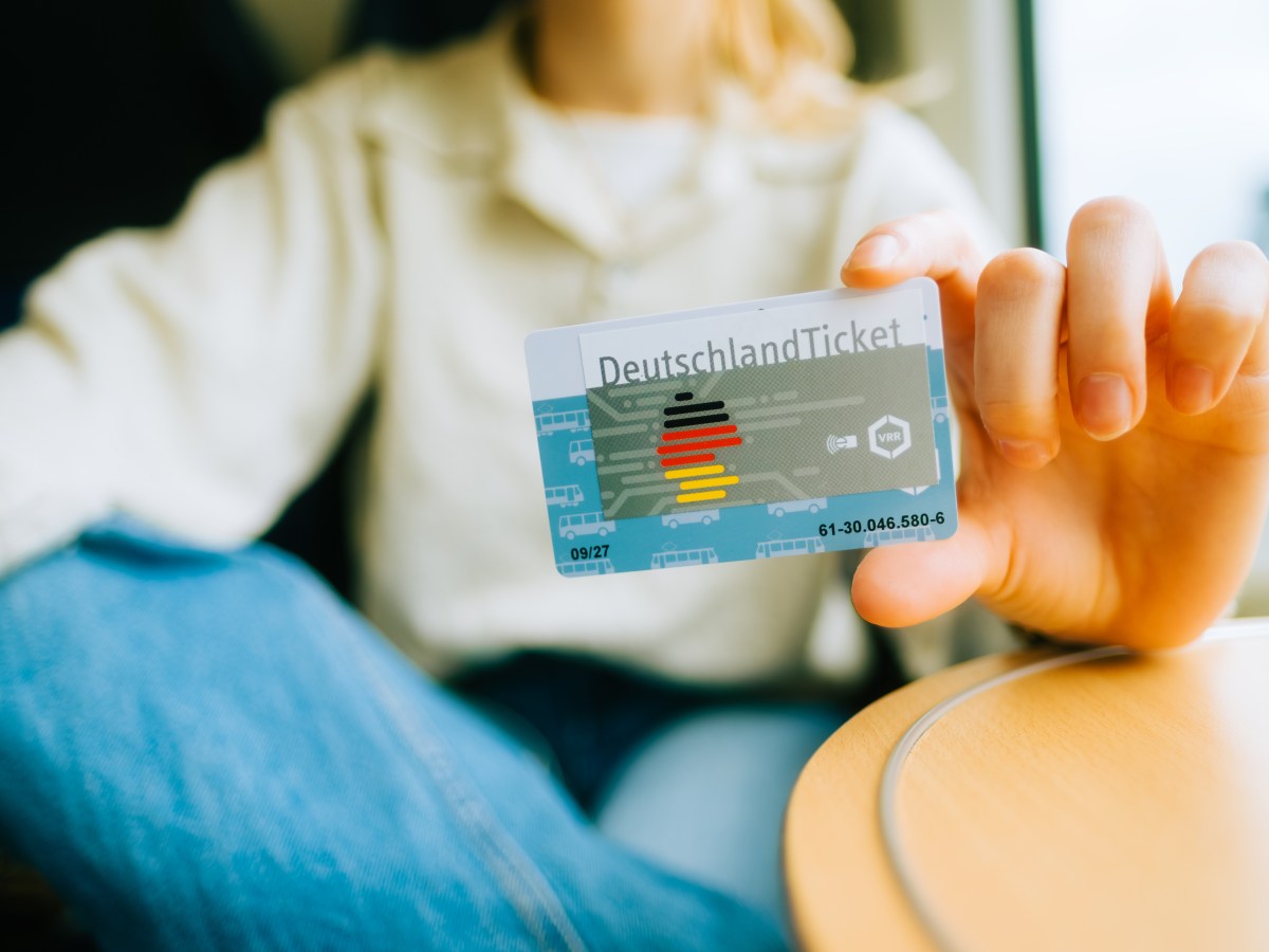 Eine Frau hÃ¤lt das Deutschlandticket in der Hand.