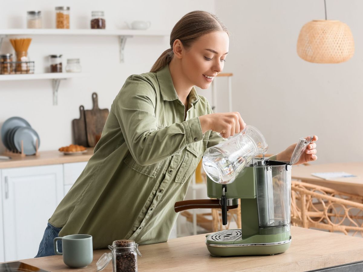 Frau fÃ¼llt Wasser in eine Kaffeemaschine