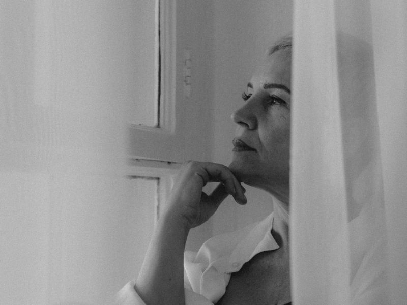 Frau in Schwarz-Weiß hinter Gardinen